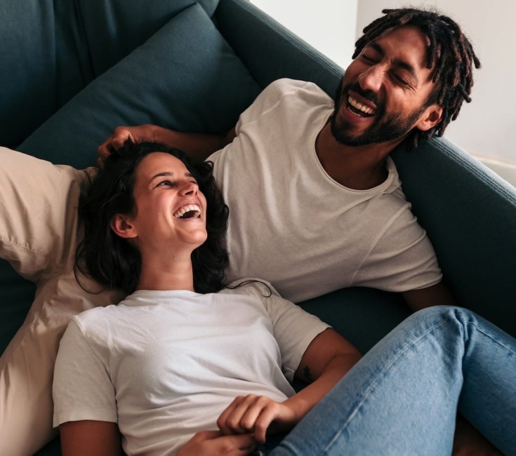a couple laughing while lounging on a couch
